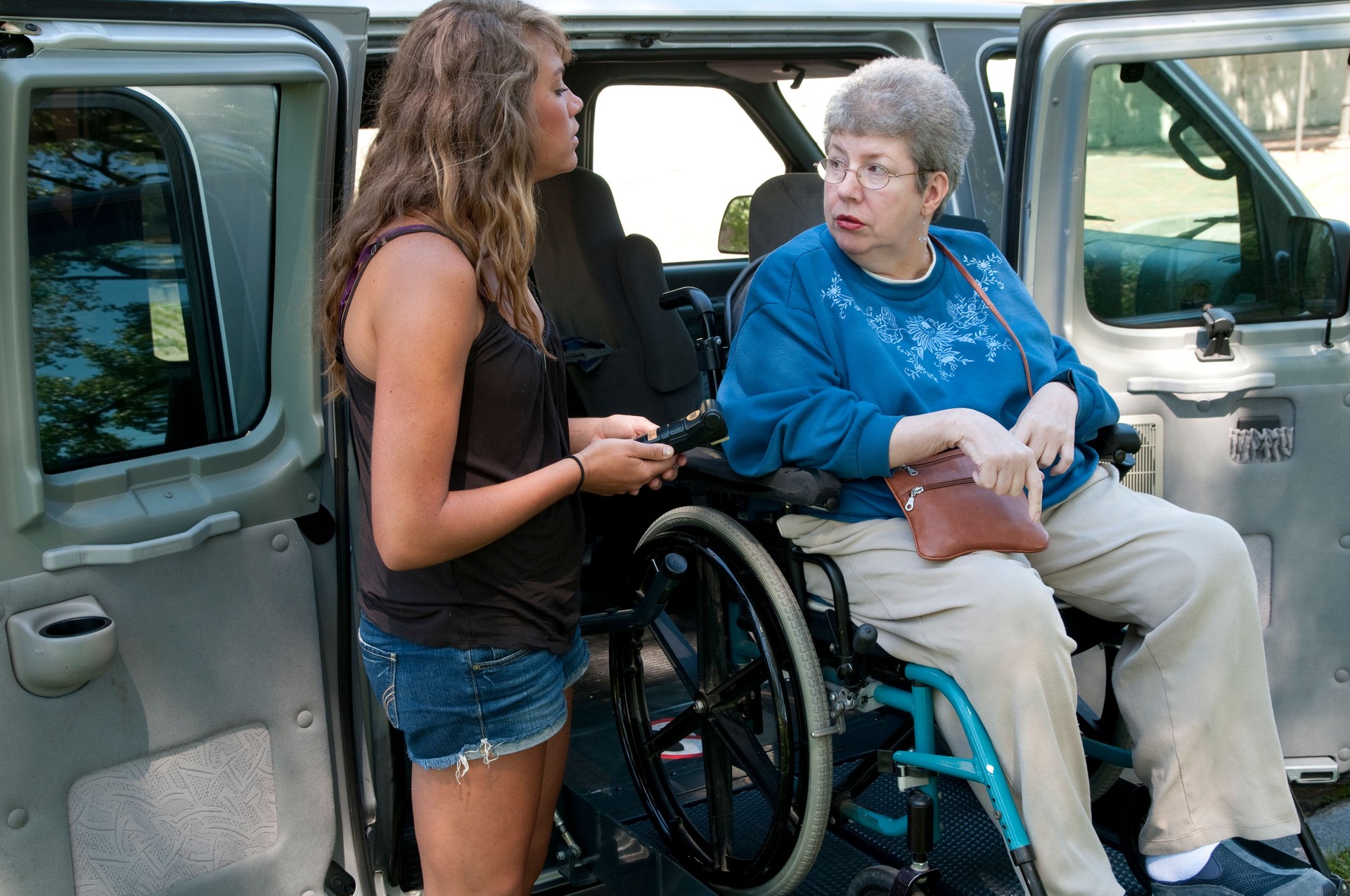 A woman uses a remote for the lift to move the wheelchair